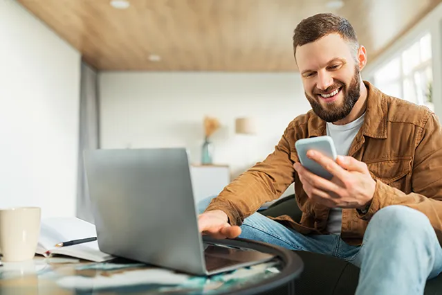 Man smiling while holding phone filling out application